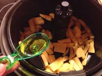 Olivenöl über die Pommes in der Heißluftfritteuse geben